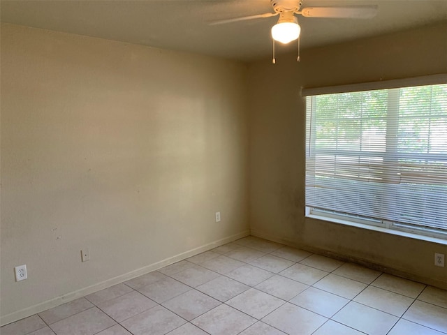 tiled empty room featuring ceiling fan and a healthy amount of sunlight