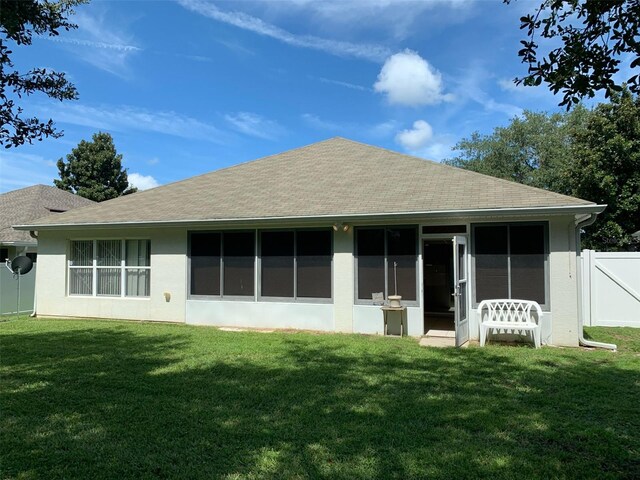 rear view of property with a sunroom and a yard