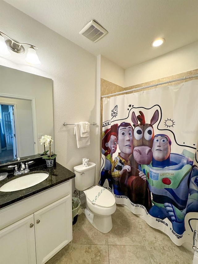 bathroom featuring a shower with shower curtain, tile patterned flooring, toilet, vanity, and a textured ceiling