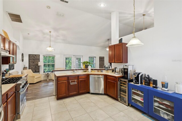 kitchen featuring stainless steel appliances, hanging light fixtures, sink, and light hardwood / wood-style flooring