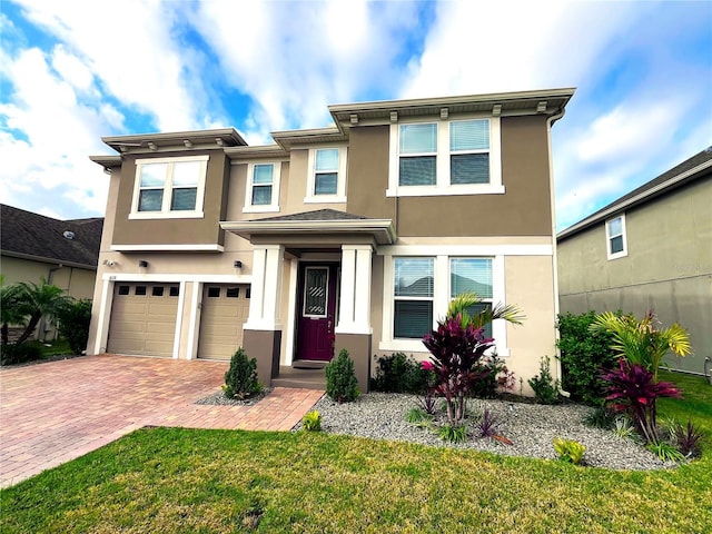 view of front facade with an attached garage, a front lawn, decorative driveway, and stucco siding