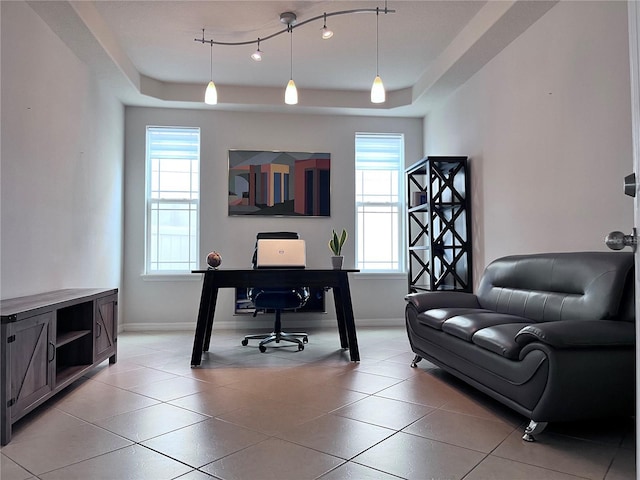 office with a healthy amount of sunlight, baseboards, a tray ceiling, and light tile patterned flooring