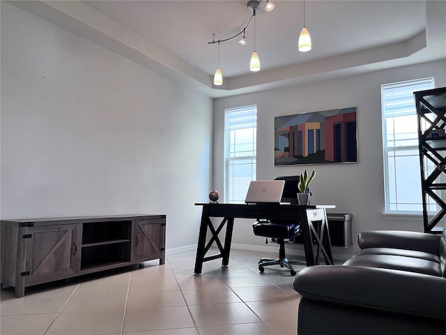 office space with a tray ceiling, a wealth of natural light, and baseboards