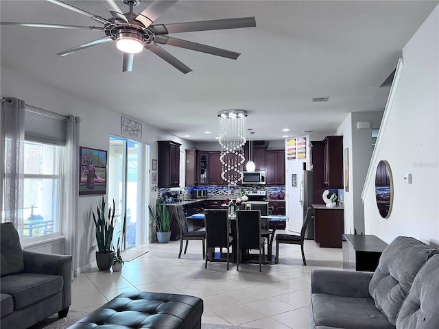 living room featuring ceiling fan with notable chandelier, visible vents, and light tile patterned flooring