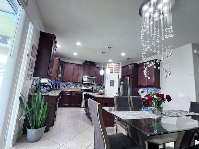 kitchen featuring appliances with stainless steel finishes, a center island, decorative backsplash, and light tile patterned floors