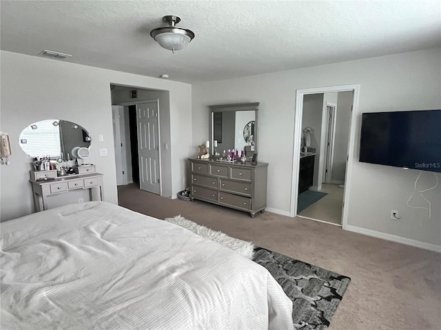 carpeted bedroom featuring a textured ceiling, connected bathroom, visible vents, and baseboards