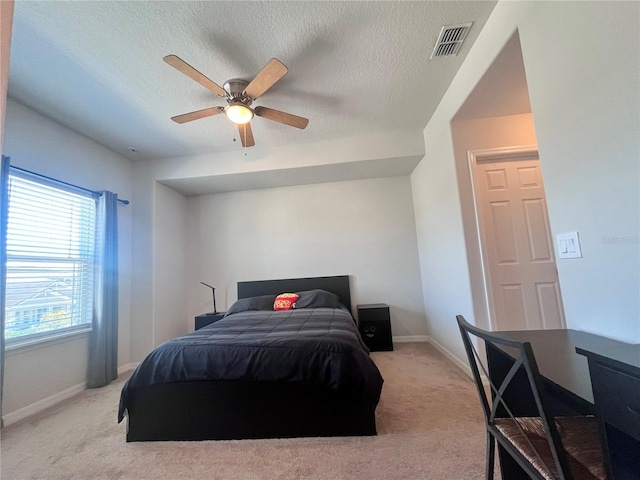 bedroom featuring light carpet, baseboards, visible vents, and a textured ceiling