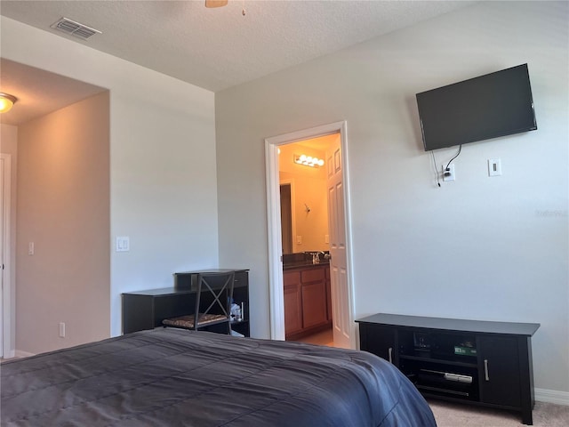 carpeted bedroom featuring visible vents, connected bathroom, and a textured ceiling