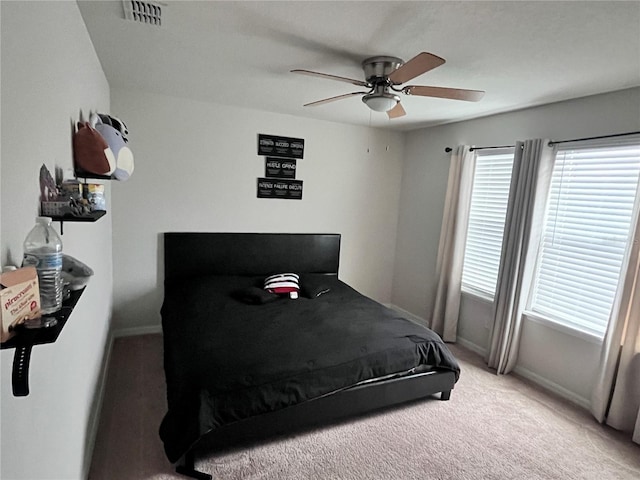 bedroom with light carpet, ceiling fan, visible vents, and baseboards