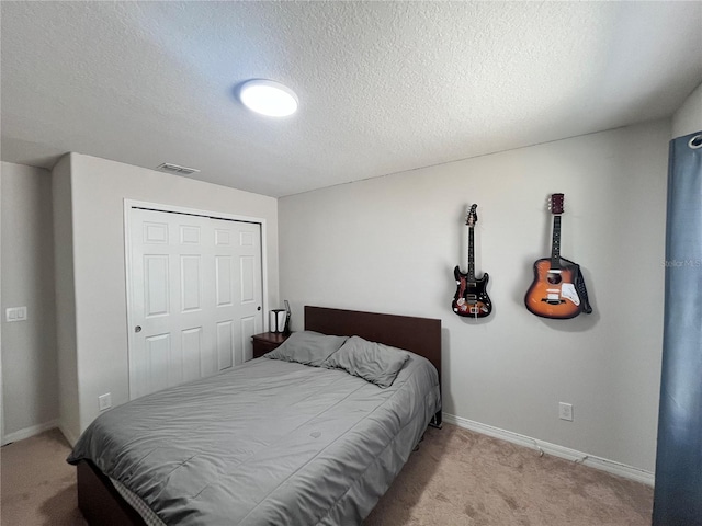 bedroom with a closet, light colored carpet, visible vents, a textured ceiling, and baseboards