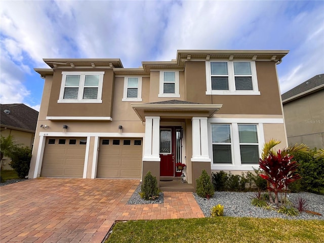 view of front of home with decorative driveway, an attached garage, and stucco siding