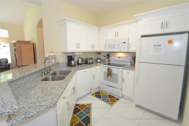 kitchen with light stone countertops, white appliances, white cabinetry, and sink