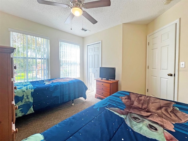 carpeted bedroom with ceiling fan, a textured ceiling, and multiple windows