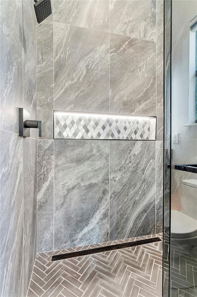 bathroom featuring toilet and a tile shower