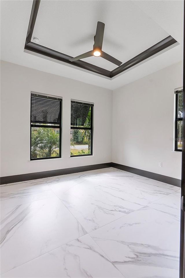 empty room with a raised ceiling and ceiling fan