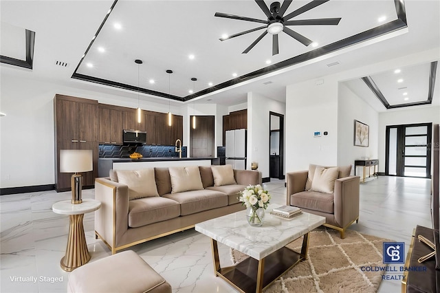 living room featuring a raised ceiling and sink