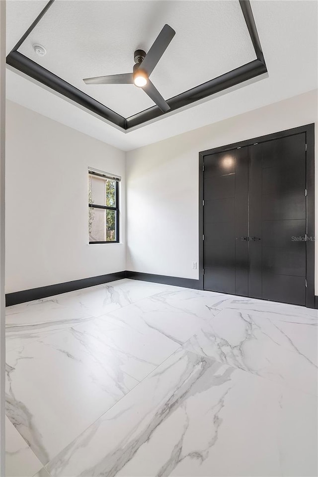 empty room featuring a raised ceiling and ceiling fan