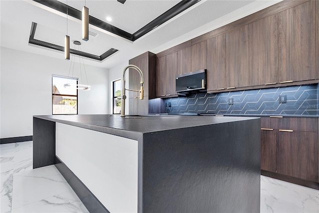 kitchen with backsplash, decorative light fixtures, a raised ceiling, and a kitchen island