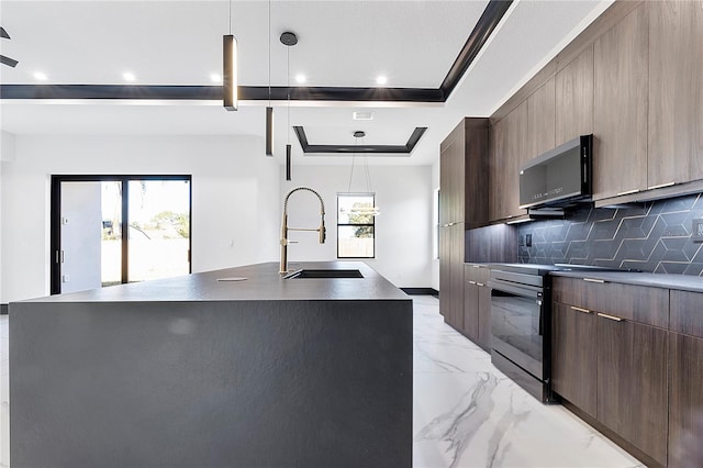 kitchen with sink, decorative light fixtures, and a center island with sink