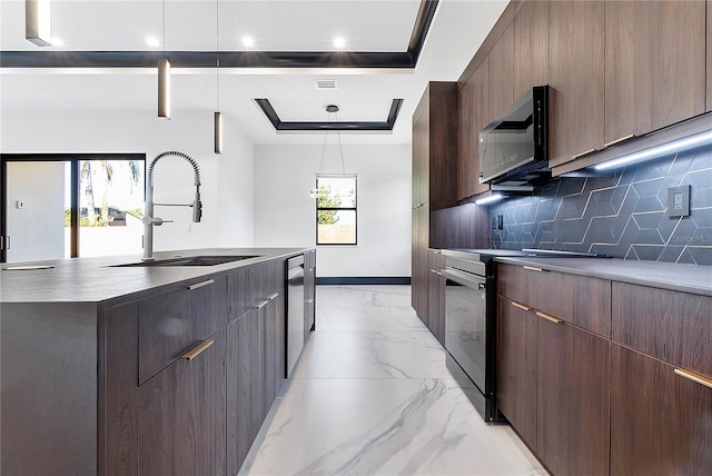 kitchen featuring pendant lighting, an island with sink, sink, backsplash, and a tray ceiling