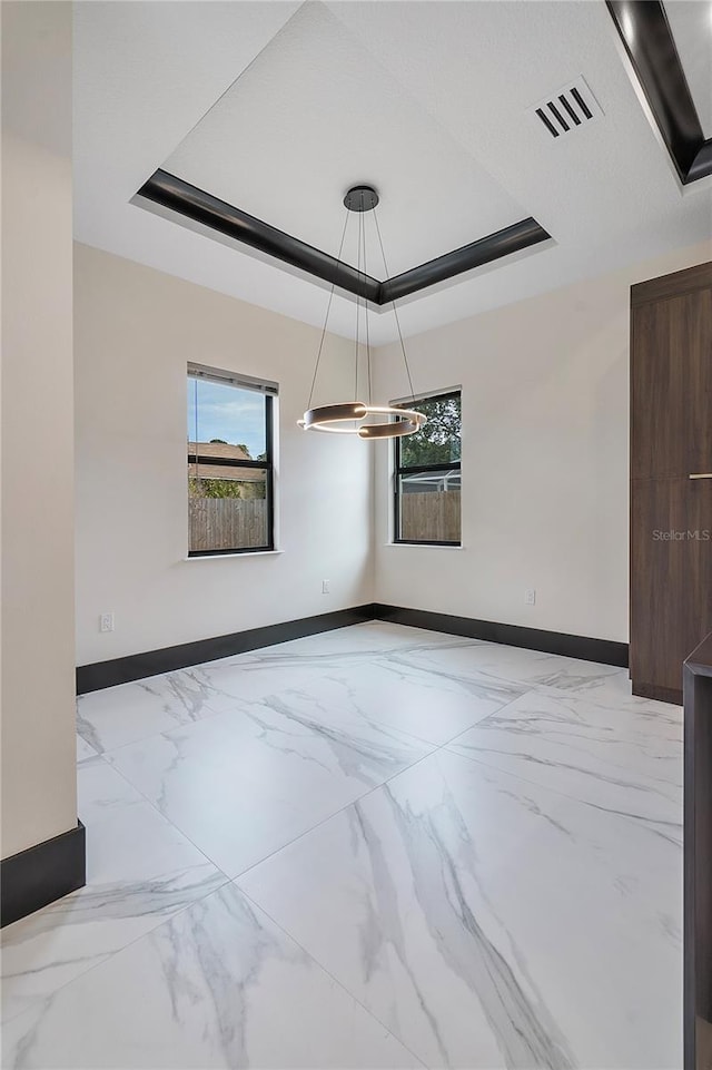 empty room with a raised ceiling and a wealth of natural light