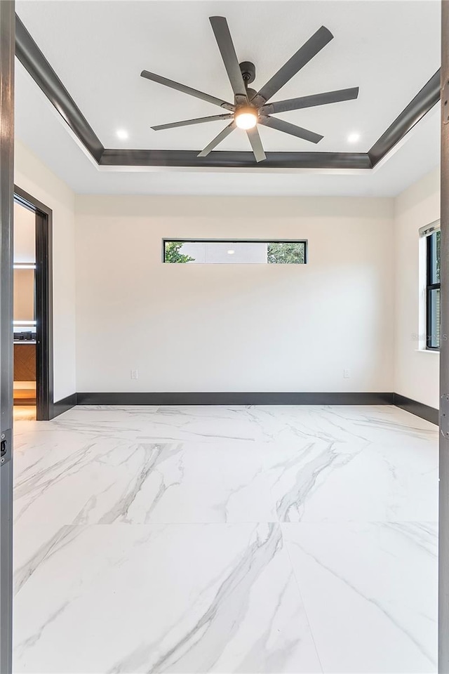 unfurnished room featuring ceiling fan and a raised ceiling