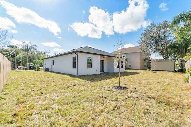 back of property featuring cooling unit, a storage shed, and a lawn