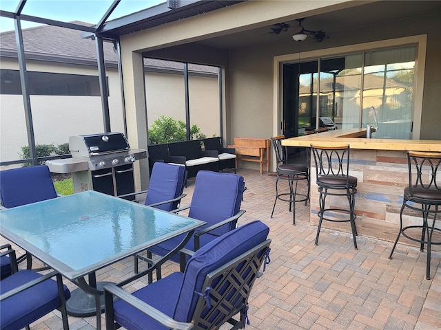 view of patio / terrace featuring ceiling fan, glass enclosure, an outdoor living space, grilling area, and exterior bar