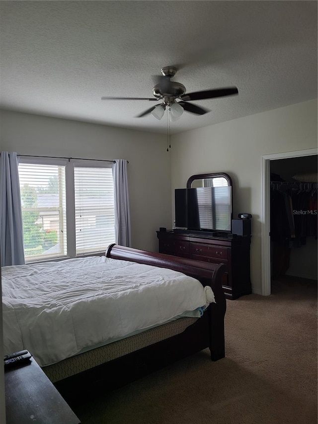 bedroom featuring ceiling fan, carpet flooring, a textured ceiling, and a walk in closet