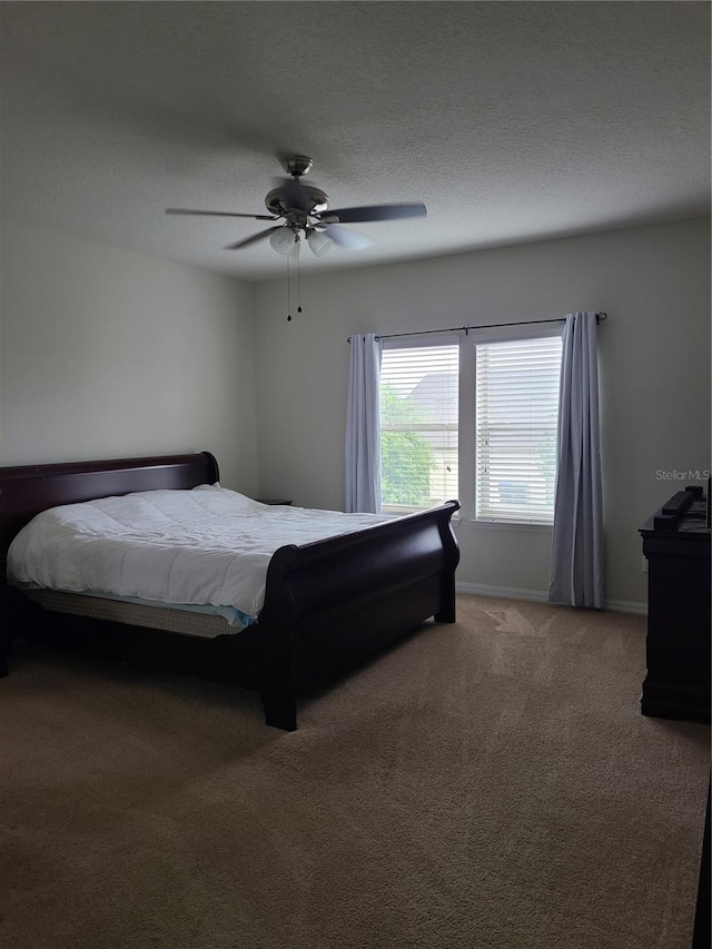 carpeted bedroom featuring ceiling fan and a textured ceiling