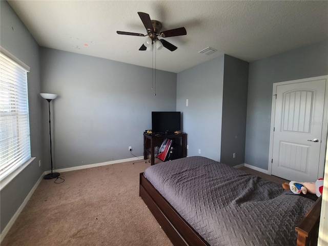 carpeted bedroom featuring ceiling fan and a textured ceiling