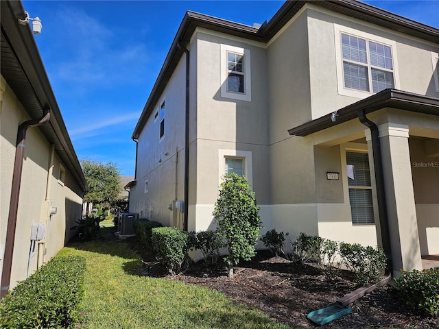 view of side of home featuring central AC unit and a lawn