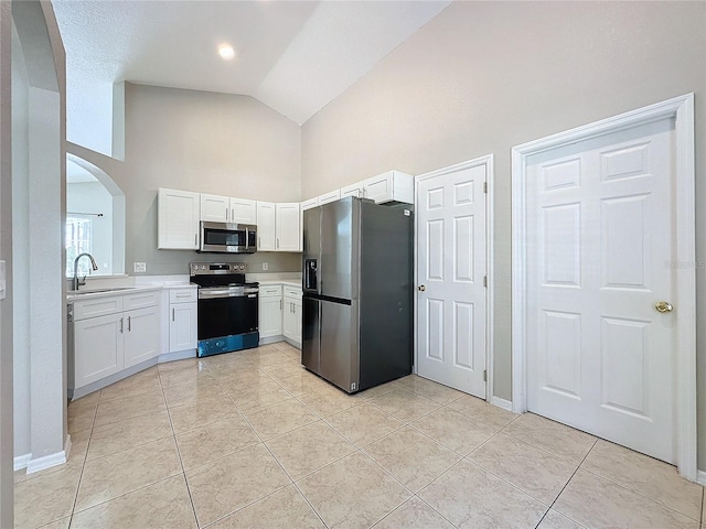 kitchen with high vaulted ceiling, sink, appliances with stainless steel finishes, and white cabinetry