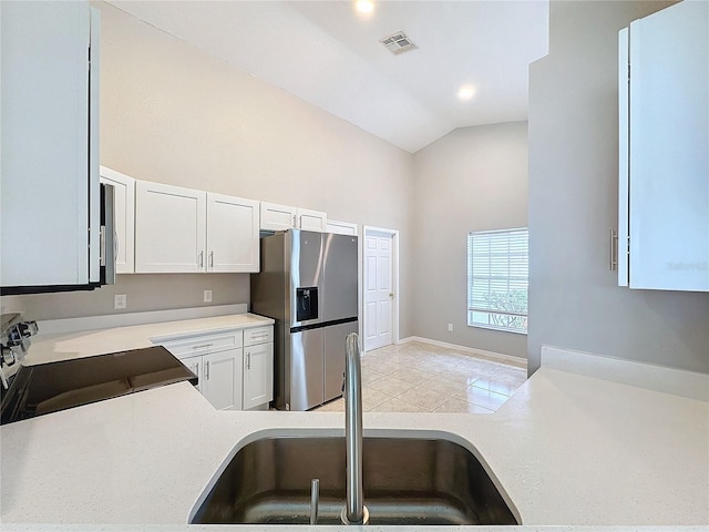 kitchen featuring stainless steel fridge, sink, electric range, lofted ceiling, and white cabinets