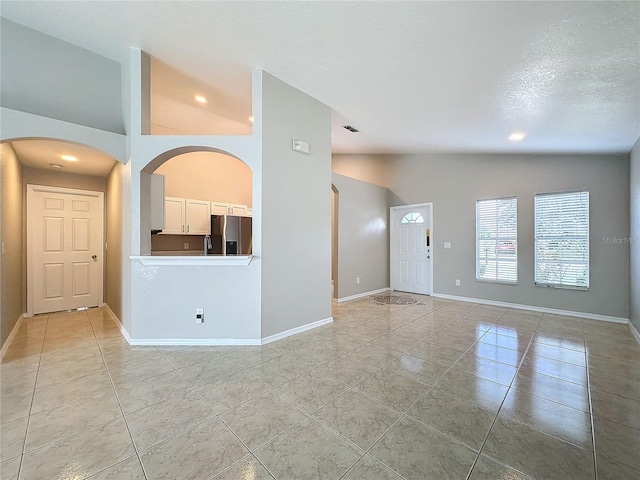 tiled empty room featuring a textured ceiling and high vaulted ceiling