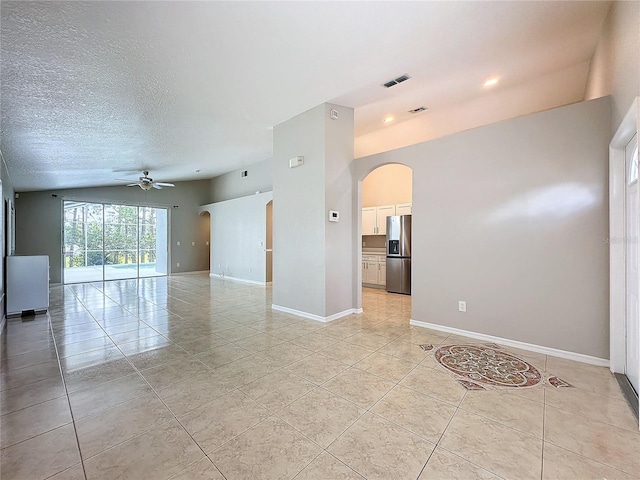 tiled empty room featuring vaulted ceiling, a textured ceiling, and ceiling fan