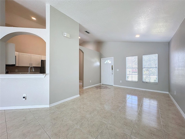 spare room featuring high vaulted ceiling, light tile patterned flooring, and a textured ceiling