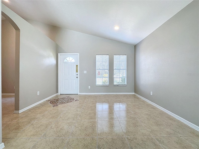 tiled entrance foyer featuring vaulted ceiling and a textured ceiling