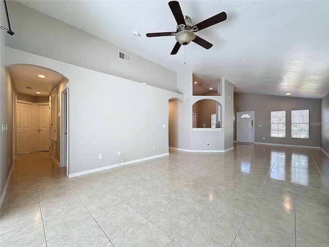 tiled empty room with vaulted ceiling, a textured ceiling, and ceiling fan