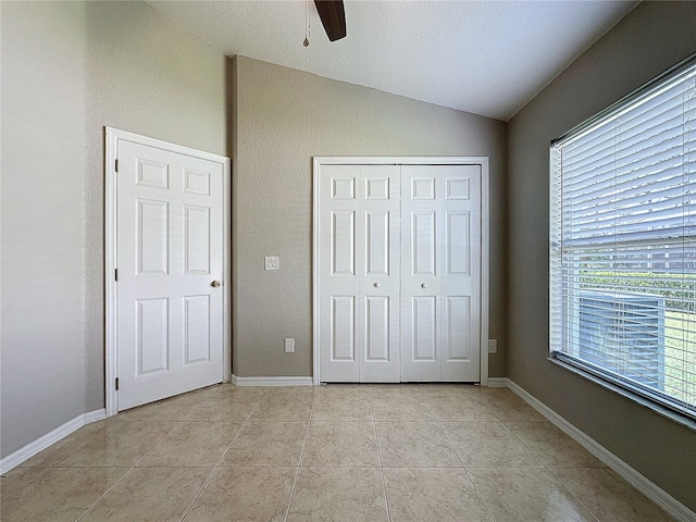 unfurnished bedroom with a closet, ceiling fan, light tile patterned floors, and vaulted ceiling