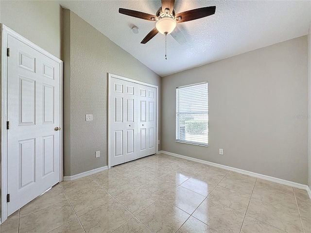 unfurnished bedroom with lofted ceiling, ceiling fan, a closet, and a textured ceiling