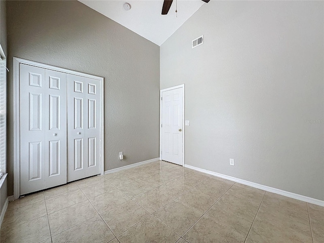 unfurnished bedroom with ceiling fan, a closet, high vaulted ceiling, and light tile patterned flooring