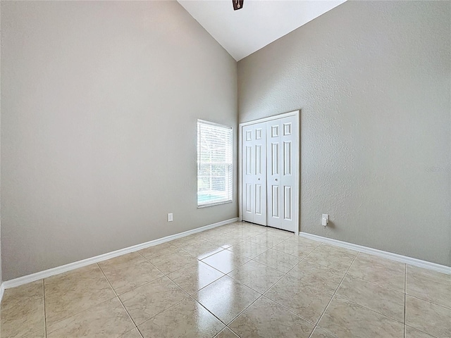 tiled spare room with high vaulted ceiling and ceiling fan