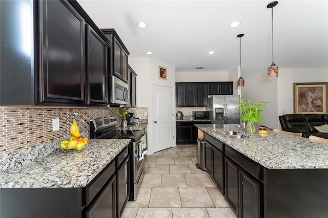 kitchen with a center island with sink, tasteful backsplash, hanging light fixtures, stainless steel appliances, and sink