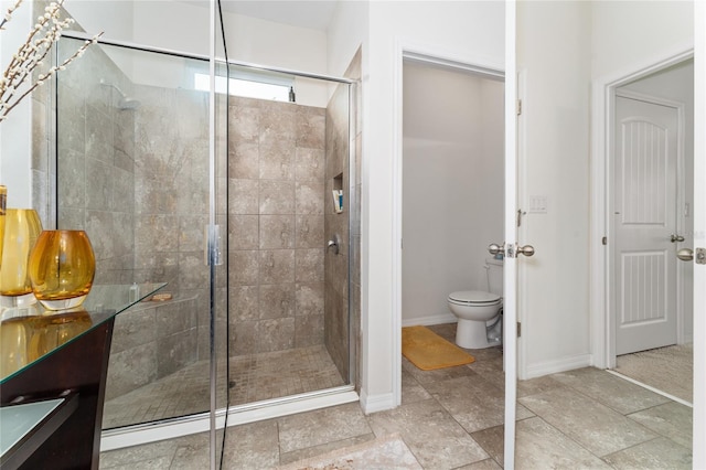 bathroom featuring toilet and a shower with shower door