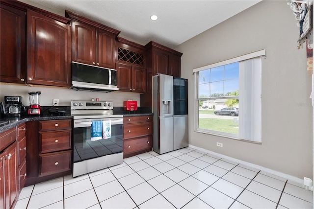 kitchen with dark stone countertops, appliances with stainless steel finishes, and light tile patterned floors