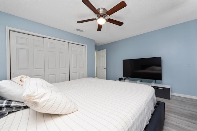 bedroom featuring wood-type flooring, a textured ceiling, ceiling fan, and a closet