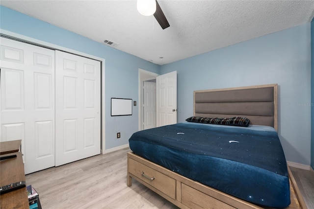 bedroom featuring ceiling fan, a closet, a textured ceiling, and light wood-type flooring