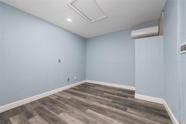 spare room featuring hardwood / wood-style flooring, a wall mounted AC, and a textured ceiling