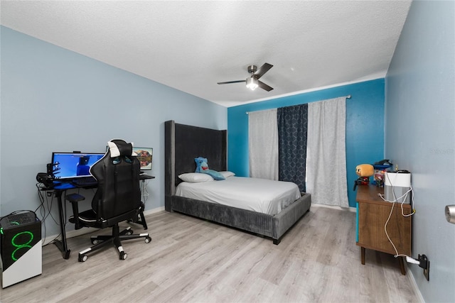 bedroom with ceiling fan, light hardwood / wood-style flooring, and a textured ceiling